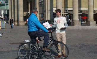 Mann übergibt Zeitung an Fahrradfahrer